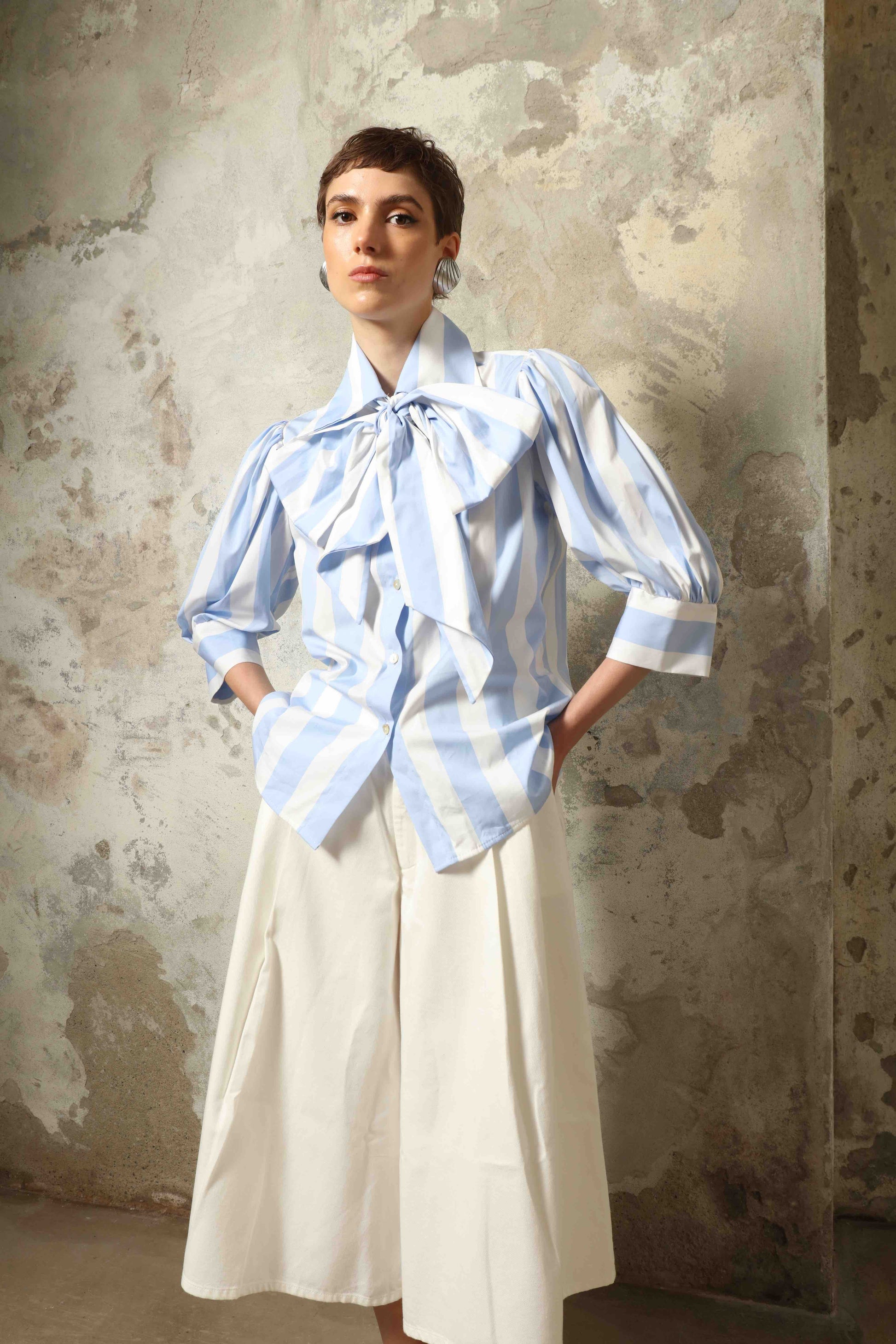 Model wearing the Karin Blue and White Macro Striped Blouse by House of Woven Stories, featuring bold macro stripes, relaxed fit silhouette, and lightweight 100% organic cotton fabric made in Italy.
