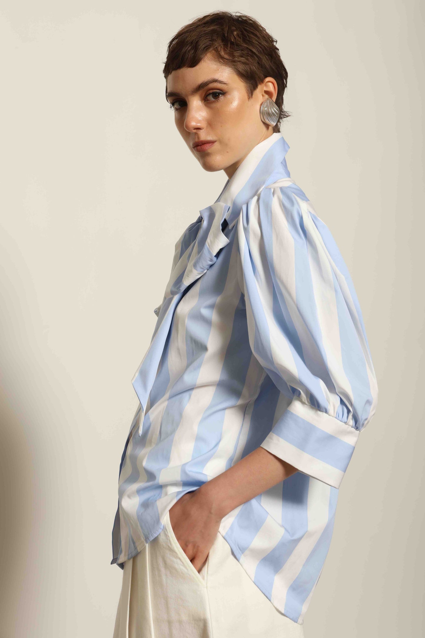 Model wearing the Karin Blue and White Macro Striped Blouse by House of Woven Stories, featuring bold macro stripes, relaxed fit silhouette, and lightweight 100% organic cotton fabric made in Italy.