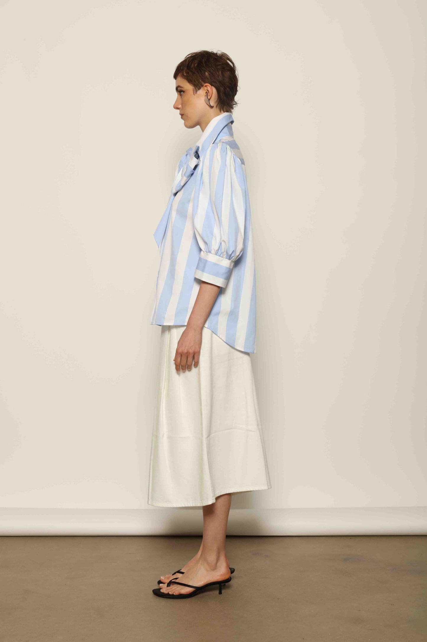 Model wearing the Karin Blue and White Macro Striped Blouse by House of Woven Stories, featuring bold macro stripes, relaxed fit silhouette, and lightweight 100% organic cotton fabric made in Italy.