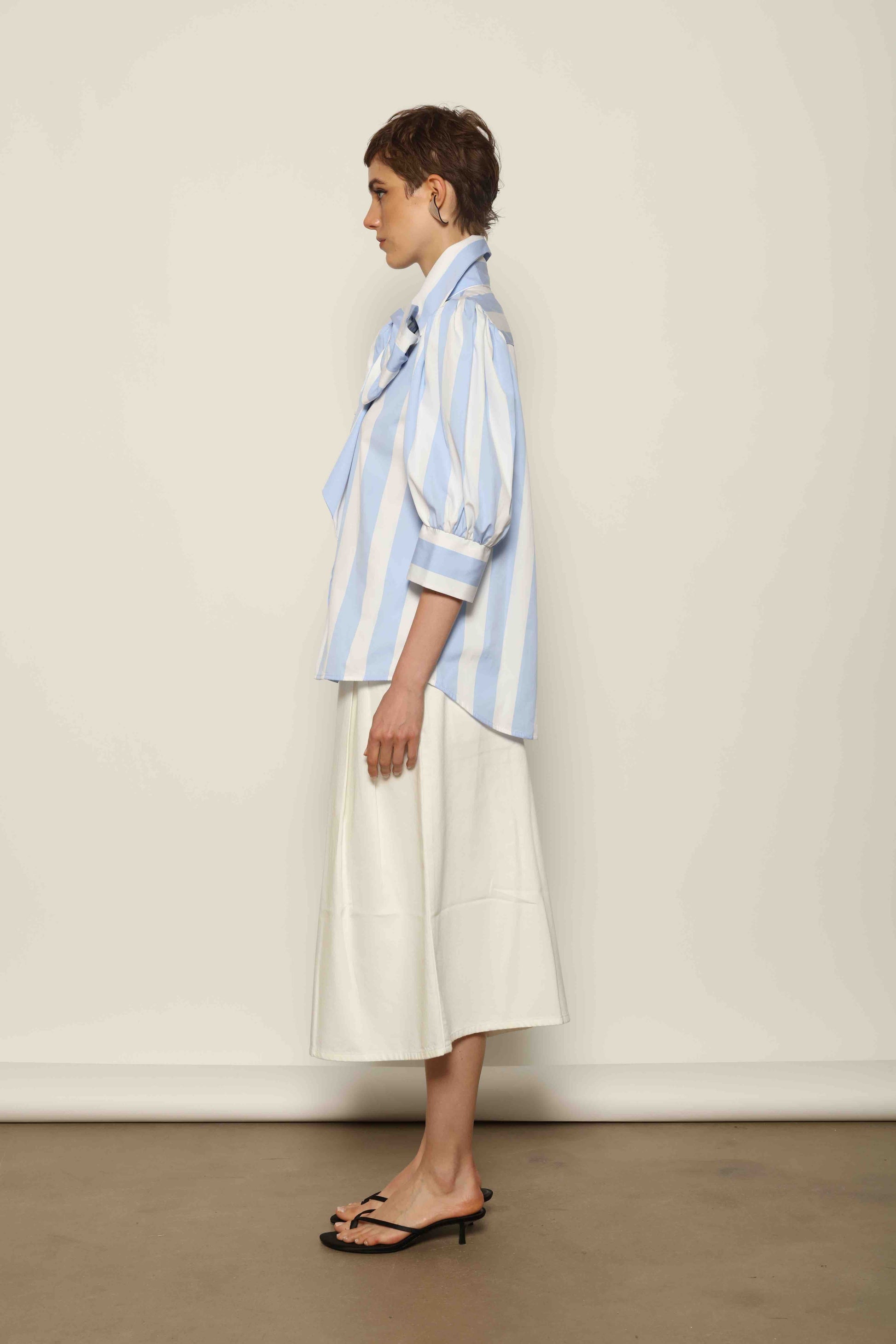 Model wearing the Karin Blue and White Macro Striped Blouse by House of Woven Stories, featuring bold macro stripes, relaxed fit silhouette, and lightweight 100% organic cotton fabric made in Italy.