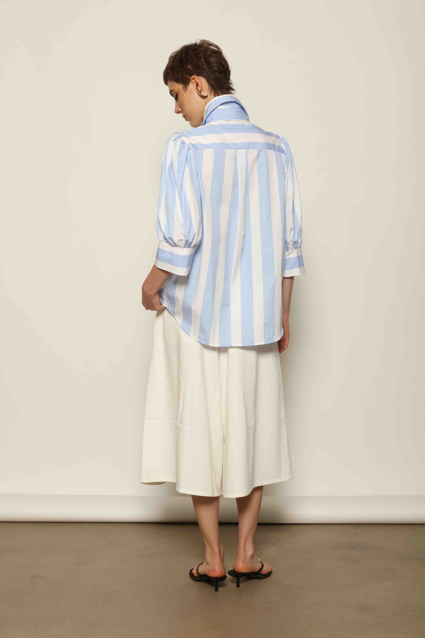 Model wearing the Karin Blue and White Macro Striped Blouse by House of Woven Stories, featuring bold macro stripes, relaxed fit silhouette, and lightweight 100% organic cotton fabric made in Italy.