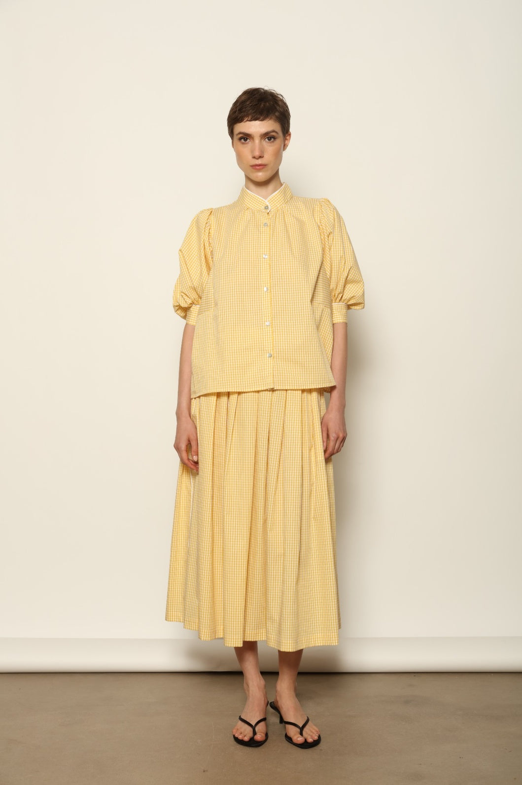 Model wearing the Lola Vichy Butter Yellow Blouse by House of Woven Stories, featuring 100% organic cotton fabric, butter yellow gingham check, short balloon sleeves, and contrasting white piping details.