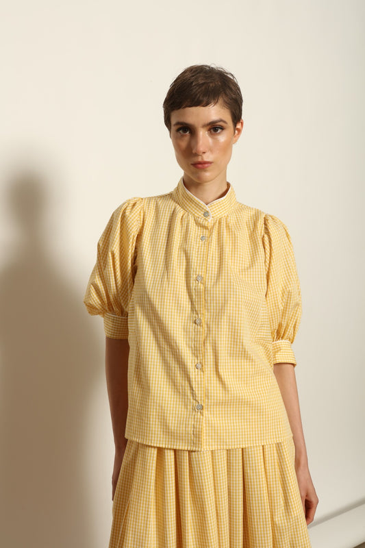 Model wearing the Lola Vichy Butter Yellow Blouse by House of Woven Stories, featuring 100% organic cotton fabric, butter yellow gingham check, short balloon sleeves, and contrasting white piping details.