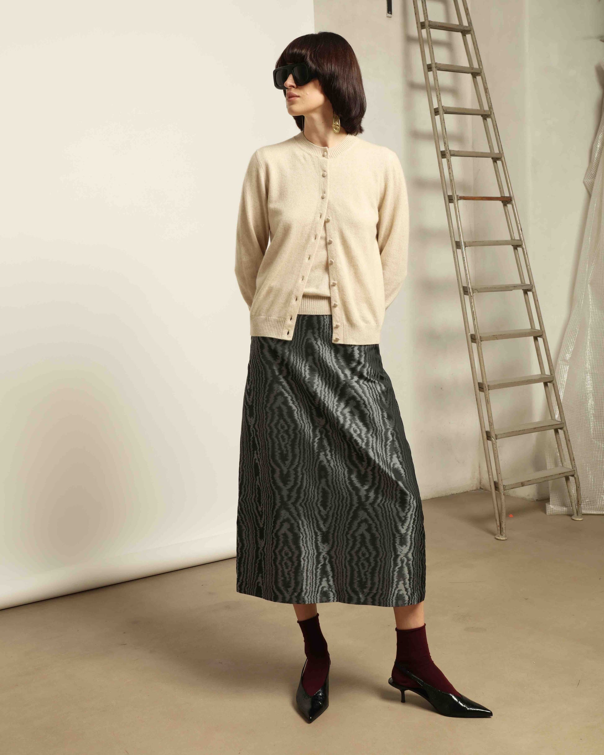 Model is wearing House of Woven Stories Nathalie Coreana Cardigan in natural undyed pure cashmere, long sleeves, round neckline, buttoned front, handmade in Italy with ultra-fine fibers from Inner Mongolia and Tibet.