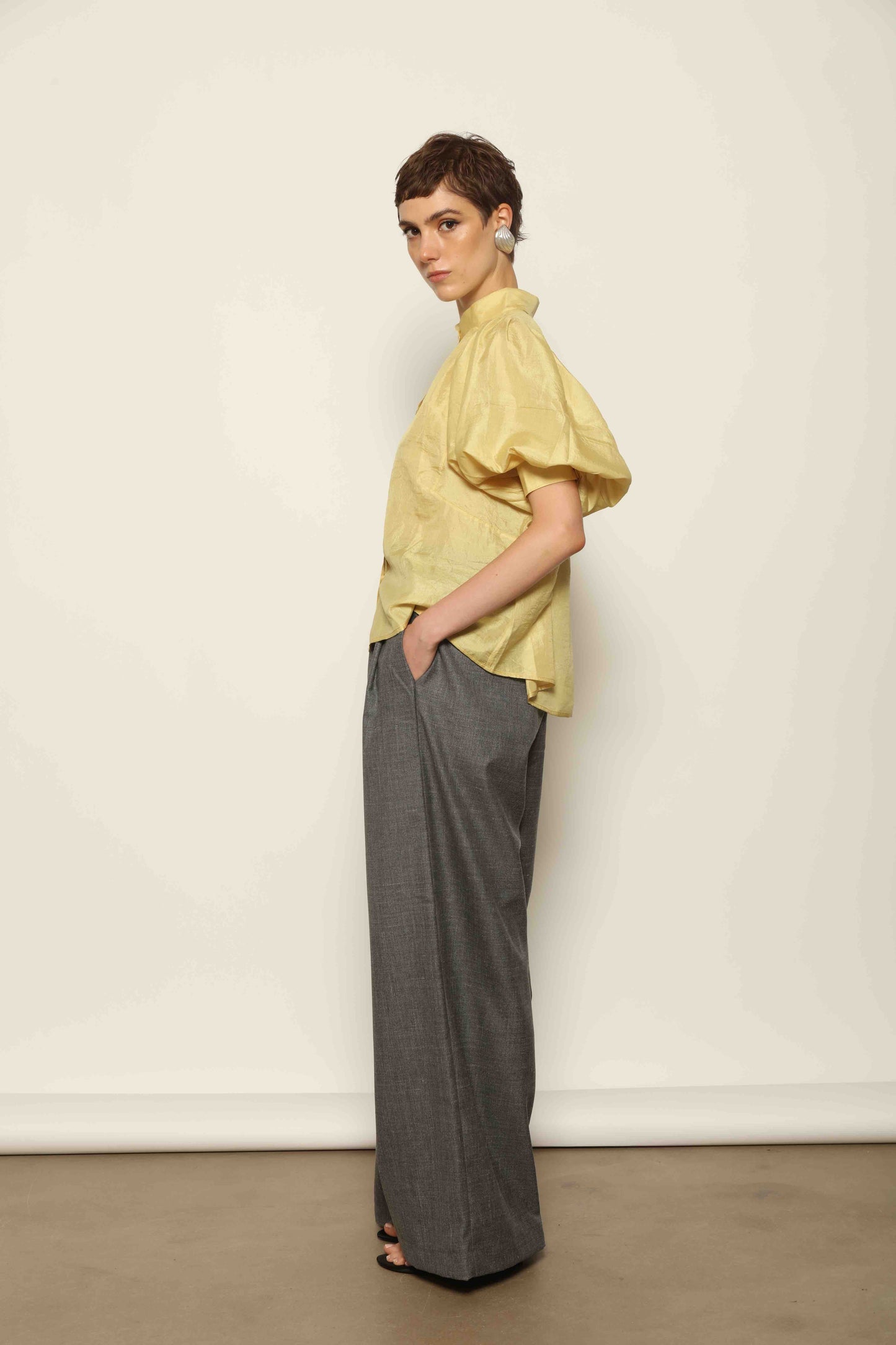 Model wearing the Lola Yellow Blouse by House of Woven Stories, crafted from naturally dyed Mulberry silk with a Mandarin collar, button-front closure, and short balloon sleeves with fitted cuffs.
