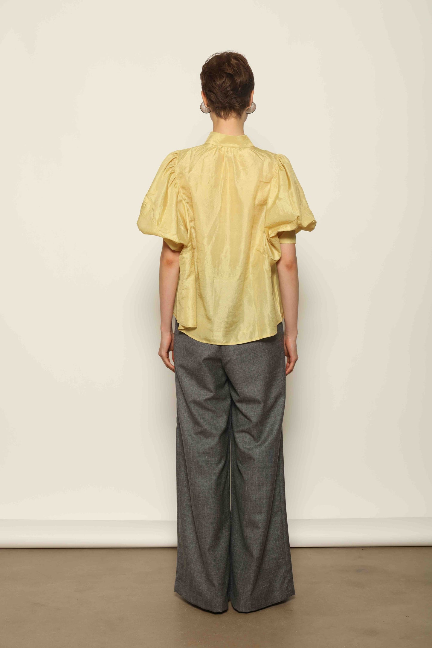 Model wearing the Lola Yellow Blouse by House of Woven Stories, crafted from naturally dyed Mulberry silk with a Mandarin collar, button-front closure, and short balloon sleeves with fitted cuffs.