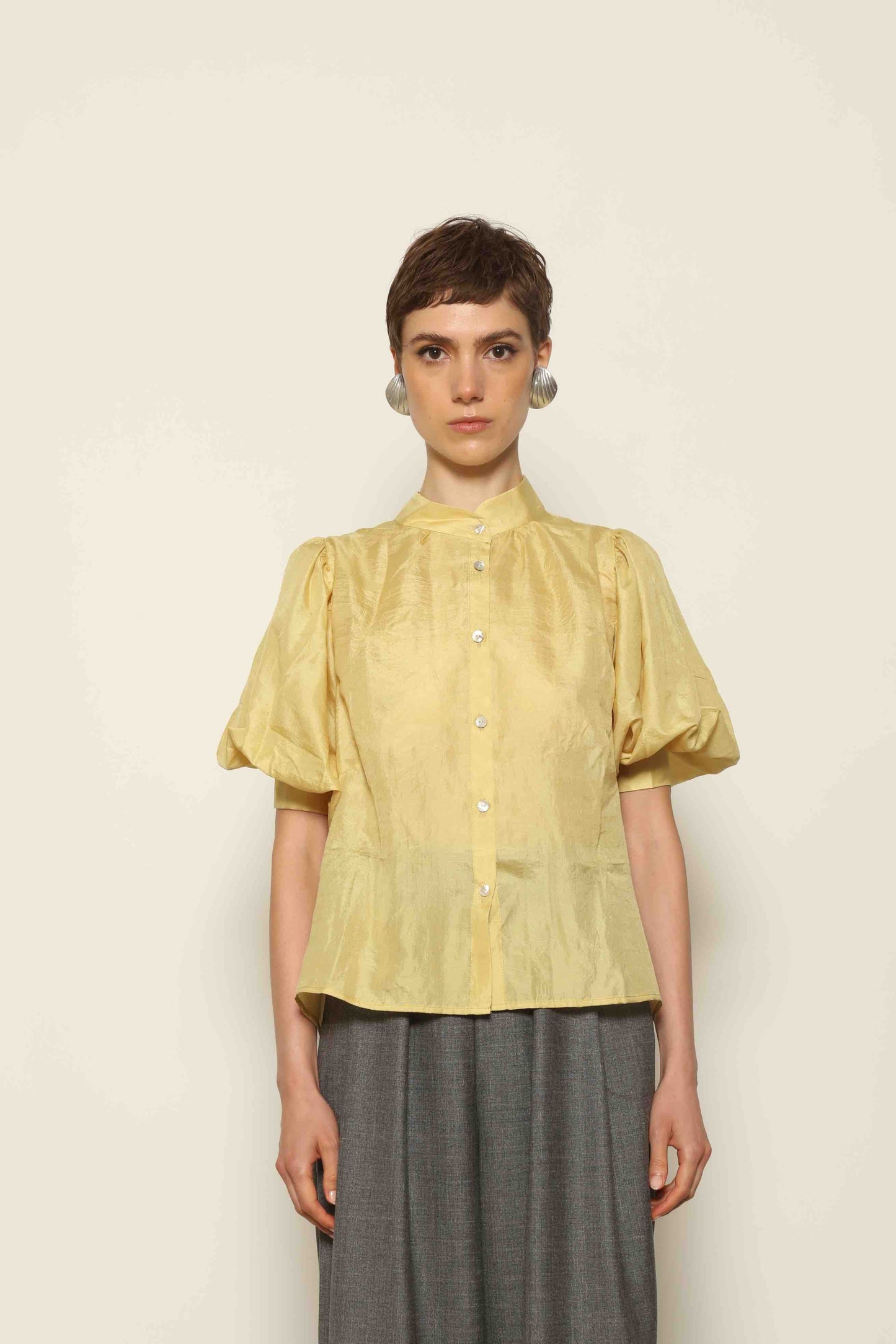 Model wearing the Lola Yellow Blouse by House of Woven Stories, crafted from naturally dyed Mulberry silk with a Mandarin collar, button-front closure, and short balloon sleeves with fitted cuffs.
