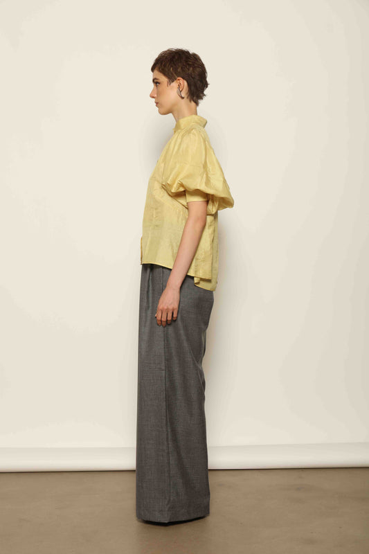 Model wearing the Lola Yellow Blouse by House of Woven Stories, crafted from naturally dyed Mulberry silk with a Mandarin collar, button-front closure, and short balloon sleeves with fitted cuffs.