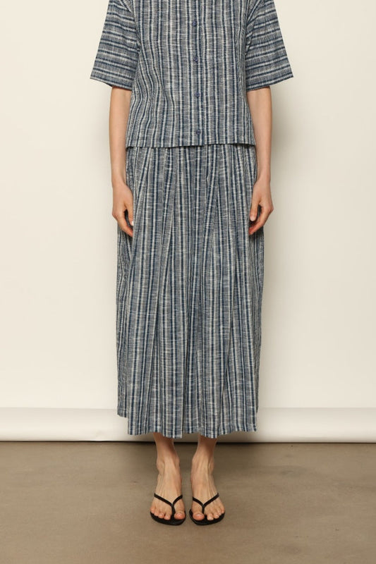 Model wearing the Seoul Indigo Blue Striped Ikat Midi Skirt by House of Woven Stories, crafted from handwoven Kala cotton with an indigo blue and off-white ikat pattern, elasticated waistband, and relaxed midi silhouette.
