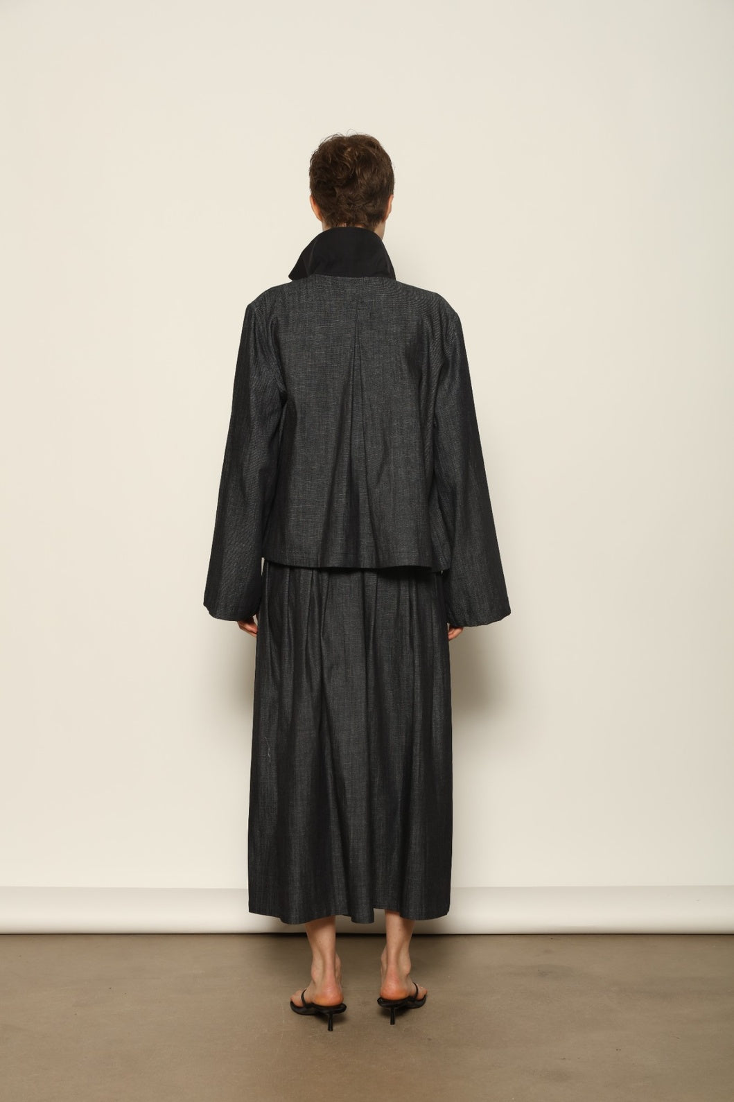 Model wearing the Seoul Ink Denim Skirt by House of Woven Stories, featuring deep indigo denim, a structured silhouette, and refined tailoring for a timeless and elegant look.