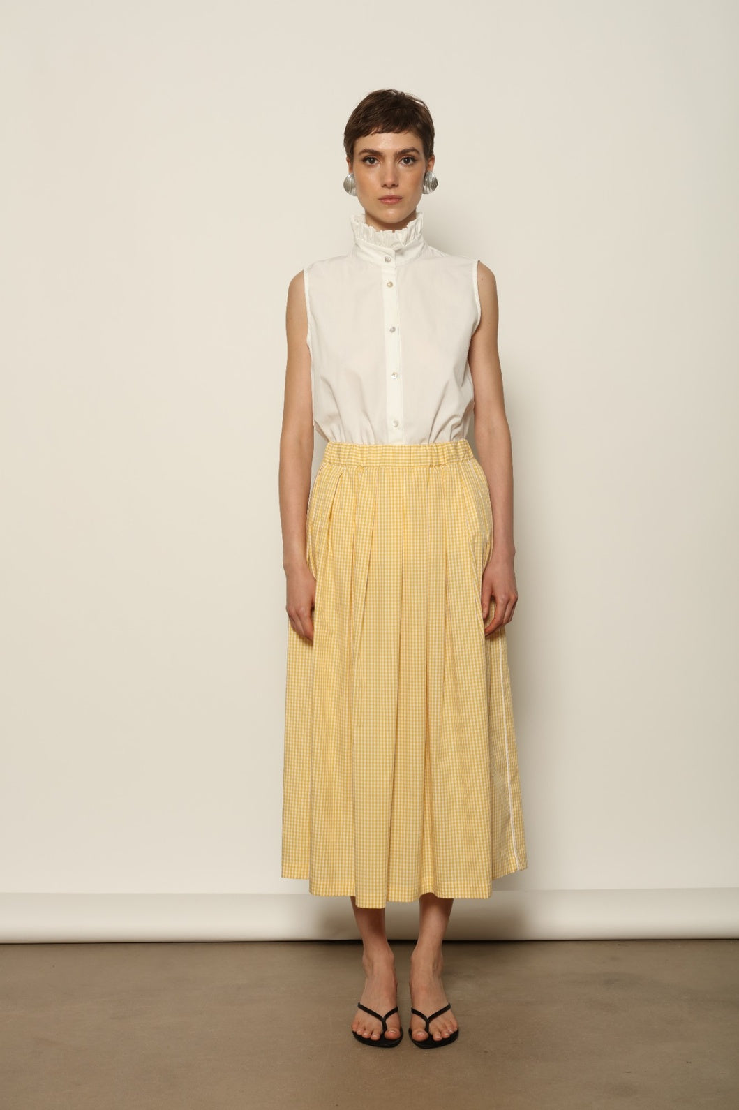 Model wearing the Seoul Vichy Butter Yellow Skirt by House of Woven Stories, featuring a butter yellow gingham pattern, draped silhouette, white piping waistband, and elegant summer design.