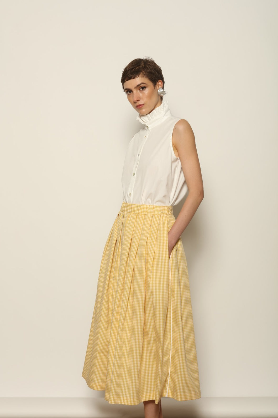 Model wearing the Seoul Vichy Butter Yellow Skirt by House of Woven Stories, featuring a butter yellow gingham pattern, draped silhouette, white piping waistband, and elegant summer design.