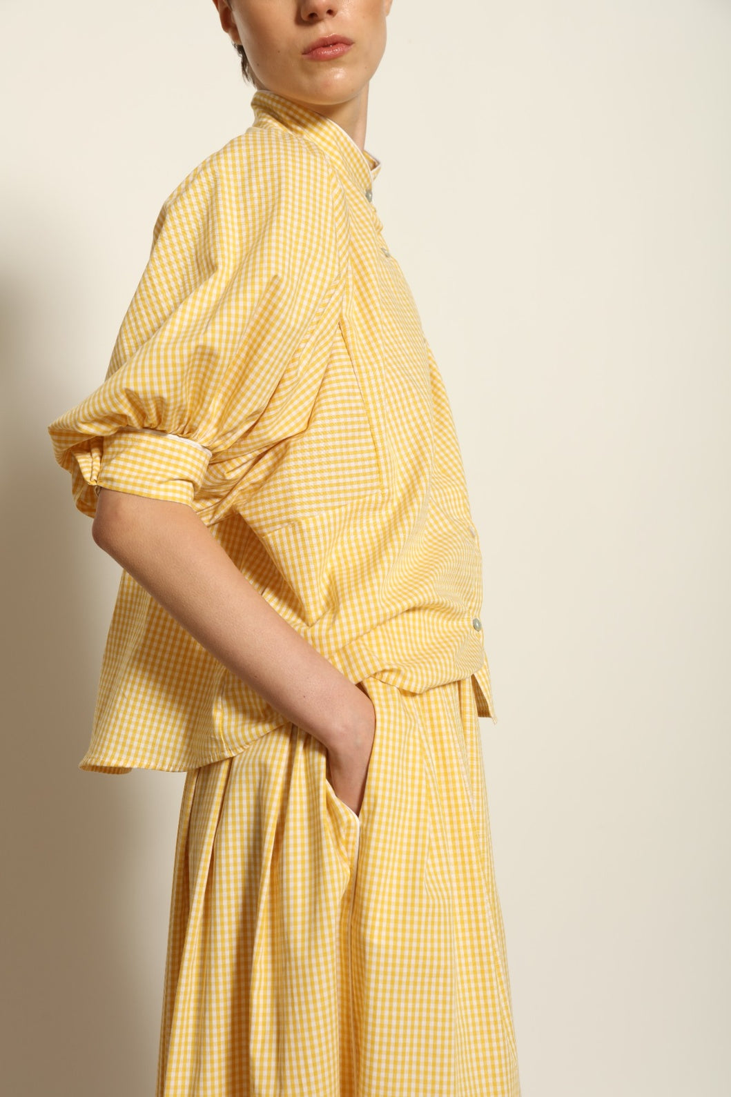 Model wearing the Seoul Vichy Butter Yellow Skirt by House of Woven Stories, featuring a butter yellow gingham pattern, draped silhouette, white piping waistband, and elegant summer design.