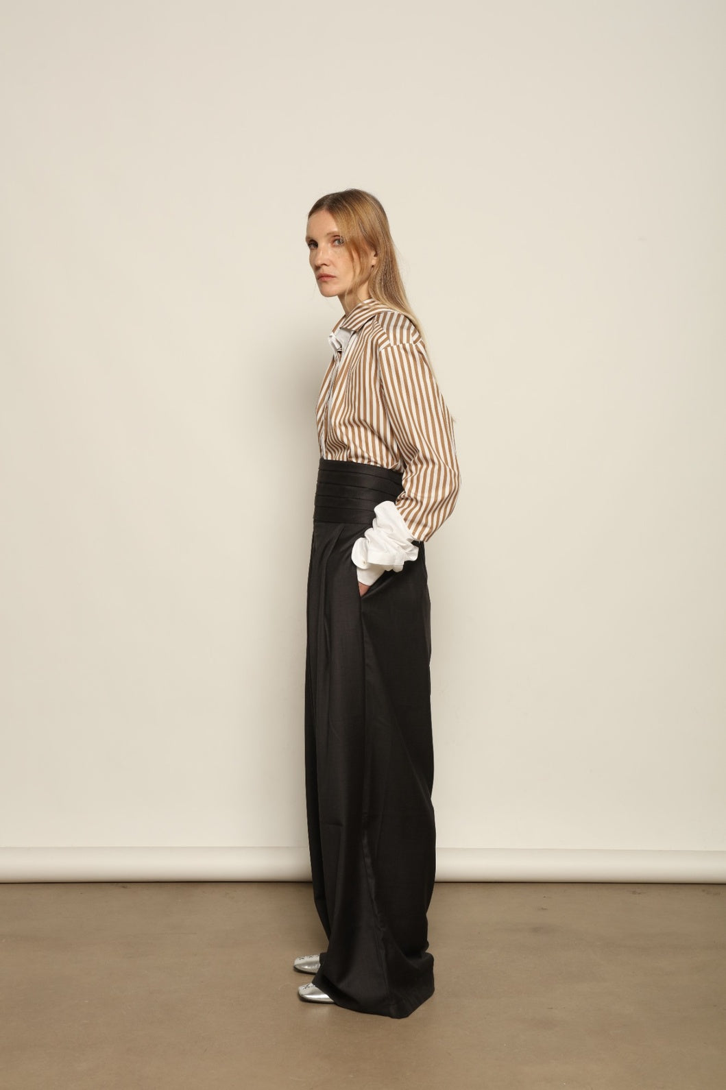 Model is wearing the Sergey Anthracite Cummerbund by House of Woven Stories, a sculptural pleated waist belt in deep anthracite designed to define the silhouette with refined elegance.
