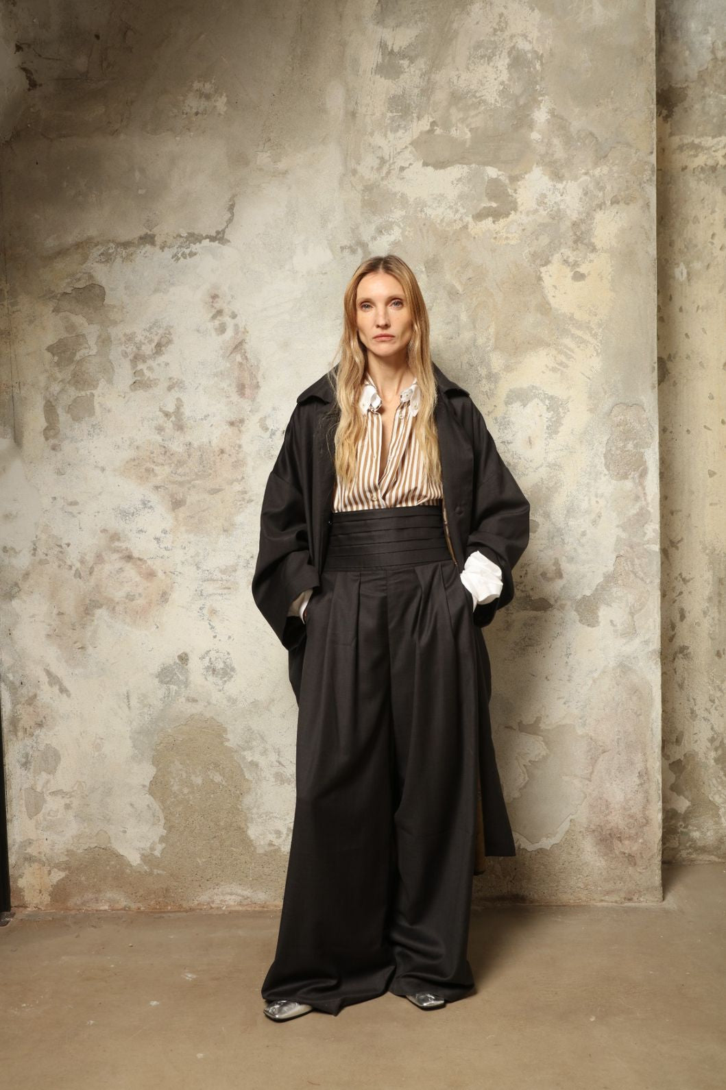 Model is wearing the Sergey Anthracite Cummerbund by House of Woven Stories, a sculptural pleated waist belt in deep anthracite designed to define the silhouette with refined elegance.