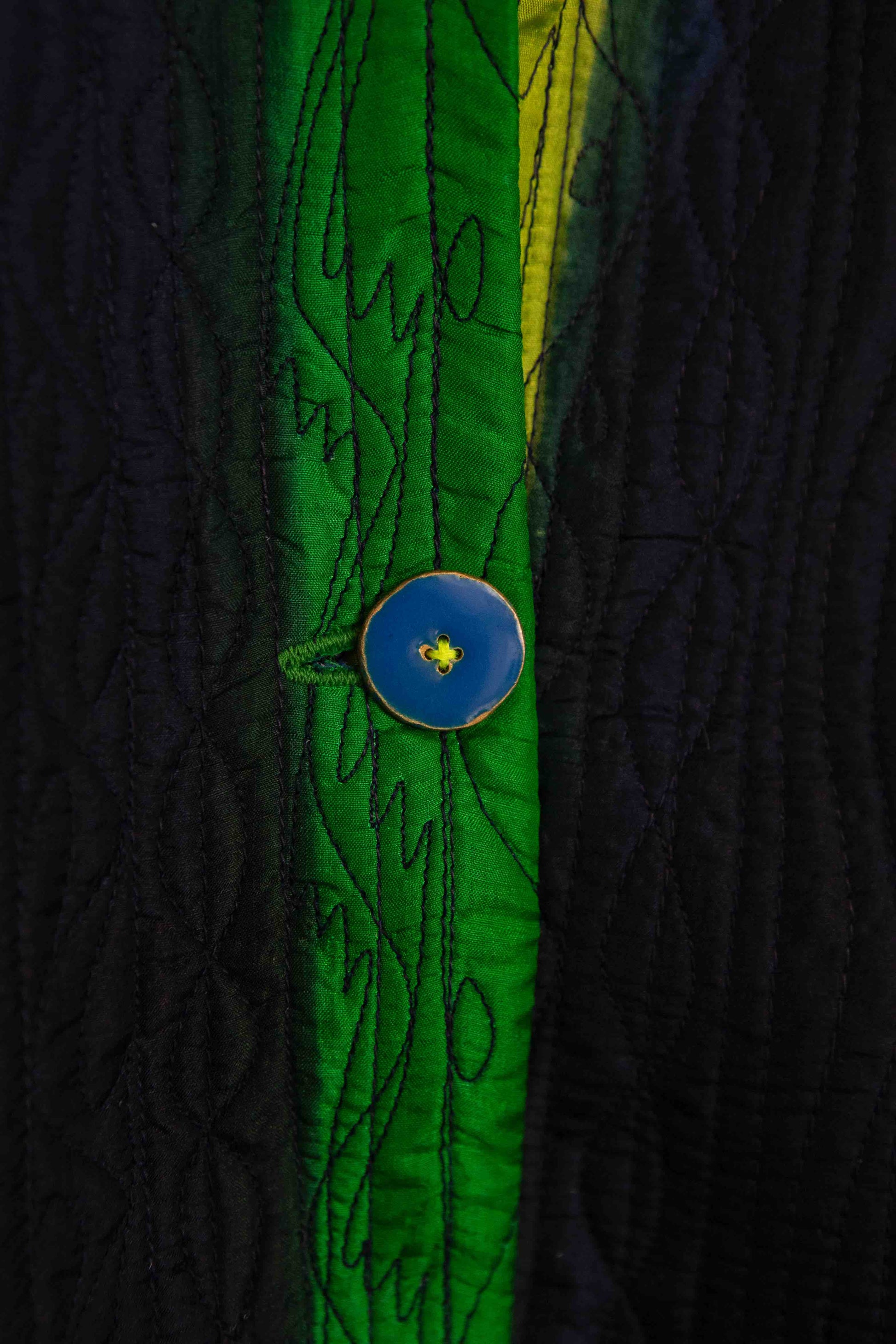Model is wearing the Folklore 18 handmade silk coat by Injiri, featuring a navy blue exterior, green lining, 100% silk, and luxurious artisan craftsmanship.