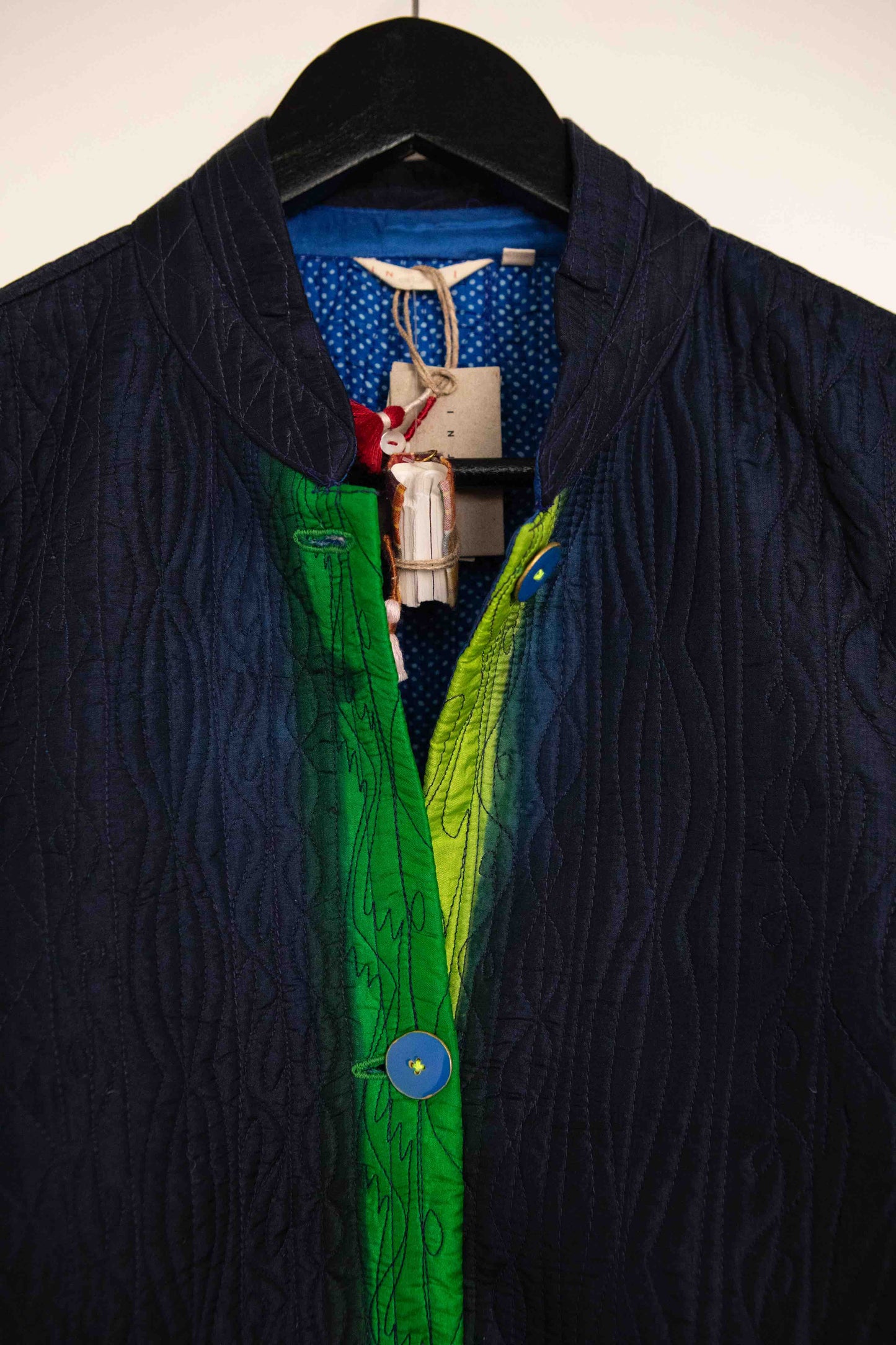 Model is wearing the Folklore 18 handmade silk coat by Injiri, featuring a navy blue exterior, green lining, 100% silk, and luxurious artisan craftsmanship.
