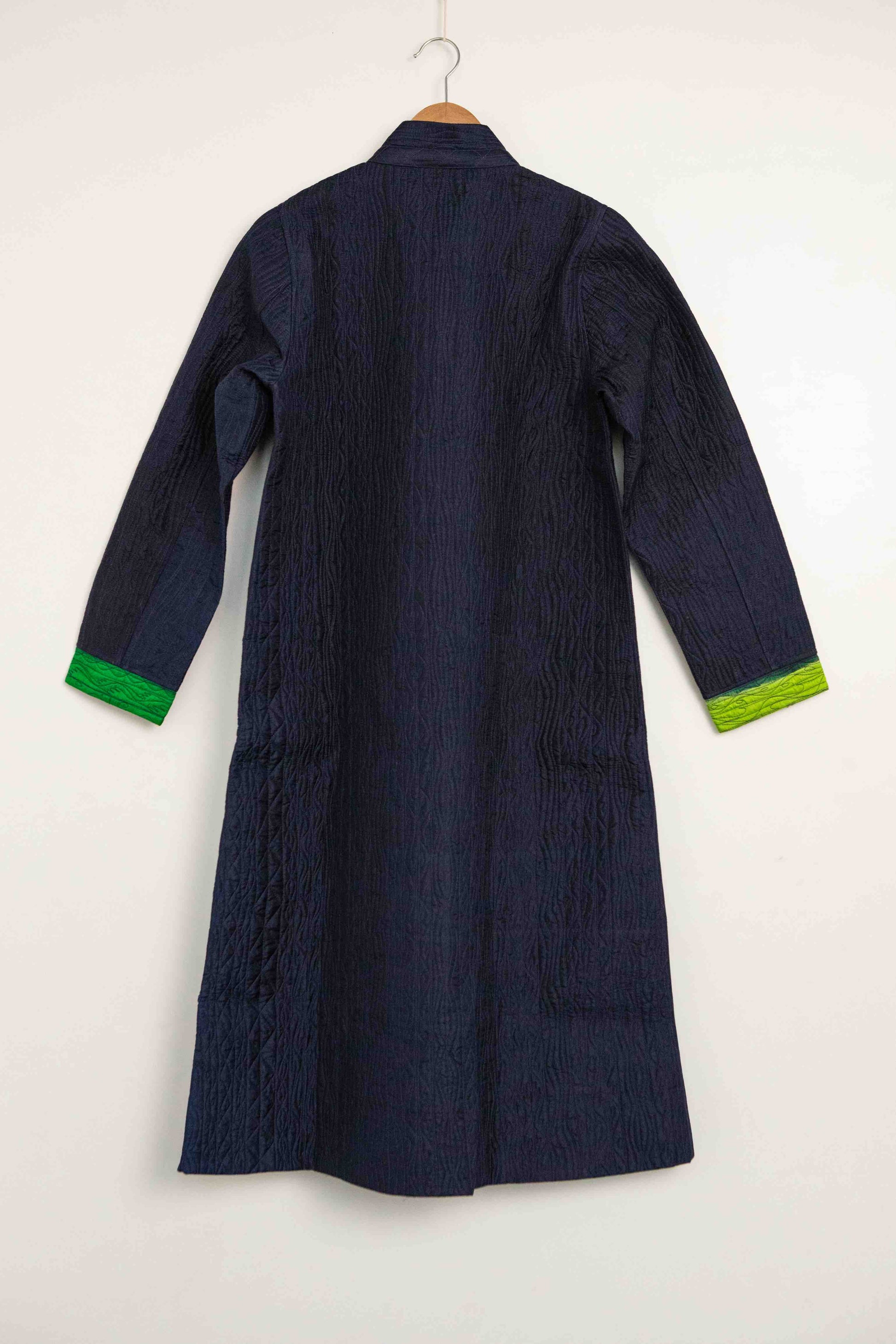 Model is wearing the Folklore 18 handmade silk coat by Injiri, featuring a navy blue exterior, green lining, 100% silk, and luxurious artisan craftsmanship.