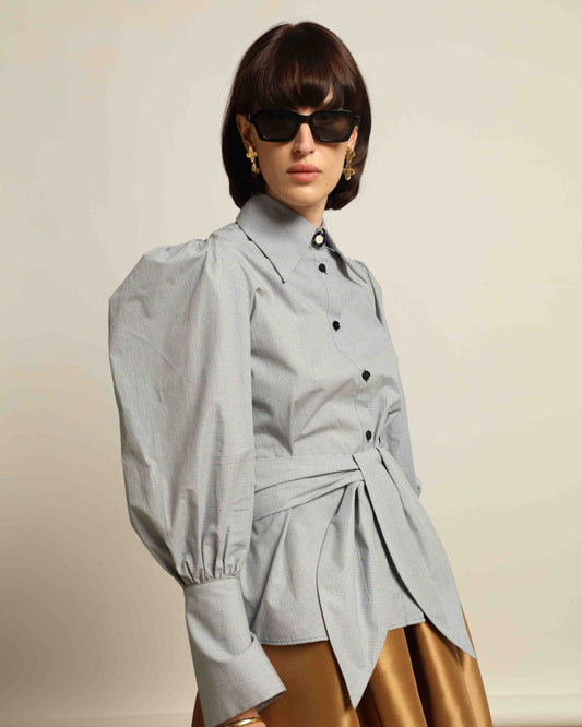 Model is wearing the Karin Micro Check Vichy Cotton Shirt by House of Woven Stories, featuring puffed sleeves, a detachable tie, and a timeless checked design, handmade in Italy from 100% organic cotton.