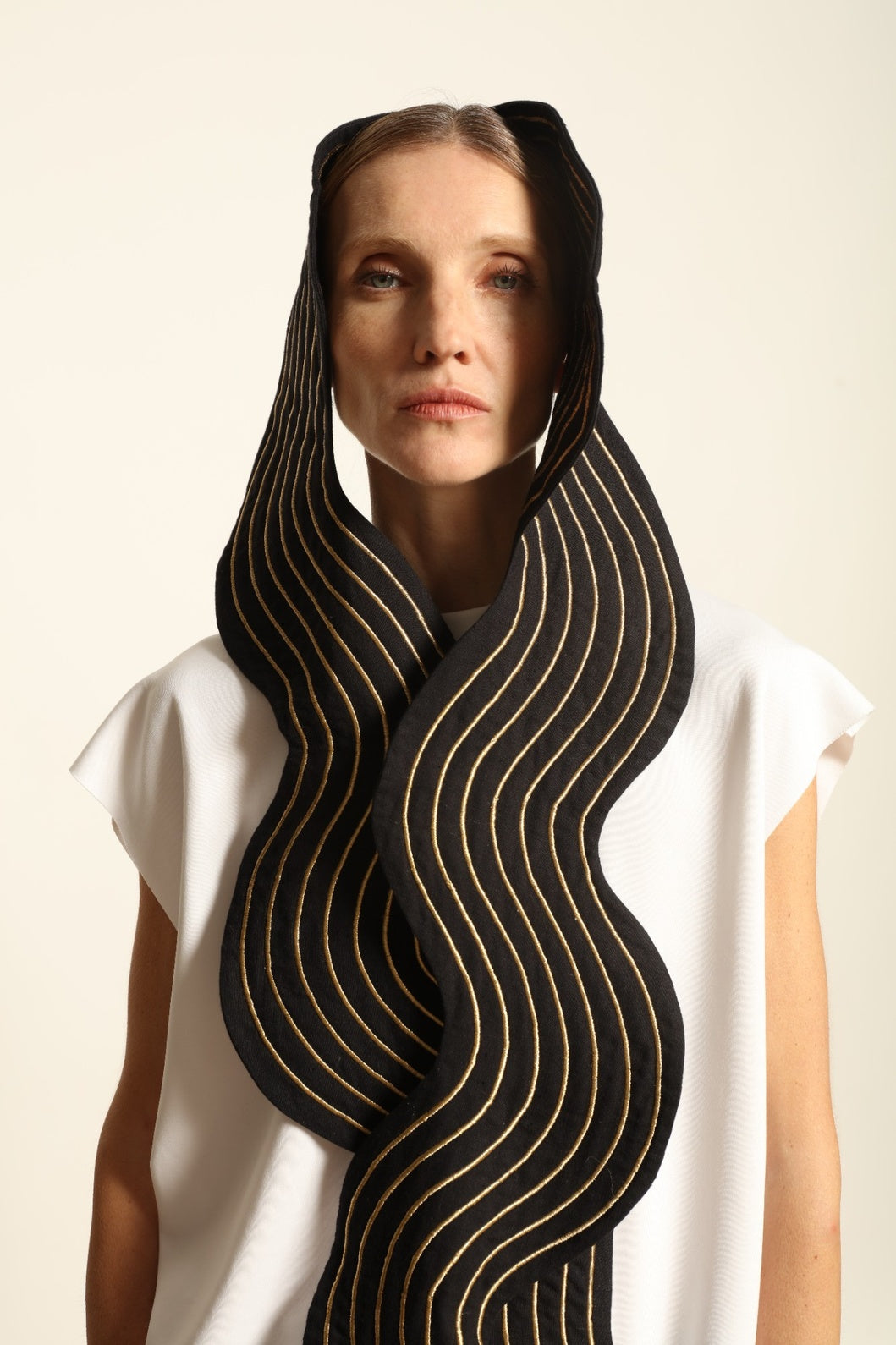 Model is wearing the Coco Curvy Scarf by Ka-Sha, a handcrafted sculptural accessory with curved folds and gold detailing, available in black and gold or white and gold, curated in the House of Woven Stories selection.
