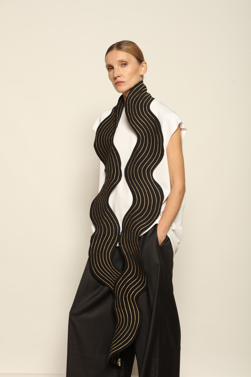 Model is wearing the Coco Curvy Scarf by Ka-Sha, a handcrafted sculptural accessory with curved folds and gold detailing, available in black and gold or white and gold, curated in the House of Woven Stories selection.