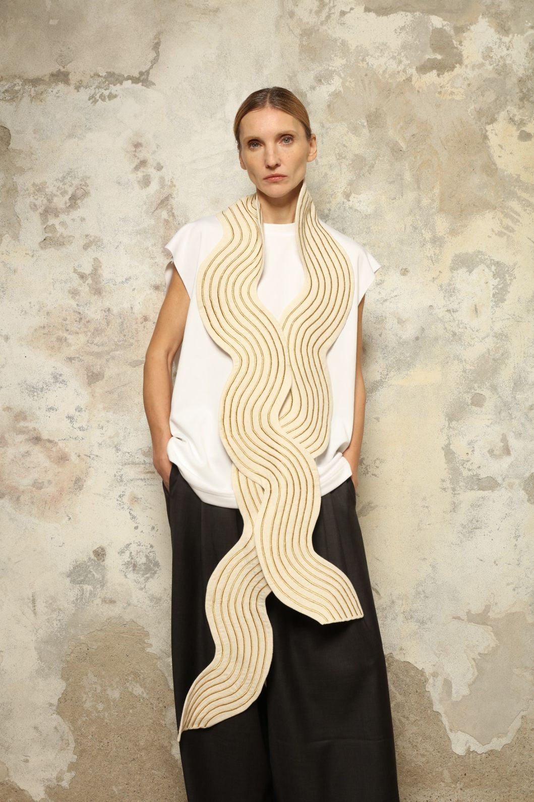 Model is wearing the Coco Curvy Scarf by Ka-Sha, a handcrafted sculptural accessory with curved folds and gold detailing, available in black and gold or white and gold, curated in the House of Woven Stories selection.