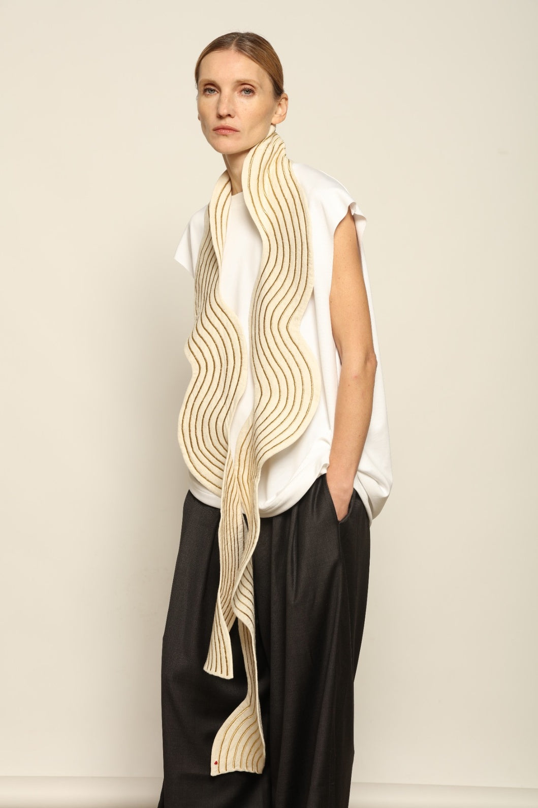 Model is wearing the Coco Curvy Scarf by Ka-Sha, a handcrafted sculptural accessory with curved folds and gold detailing, available in black and gold or white and gold, curated in the House of Woven Stories selection.