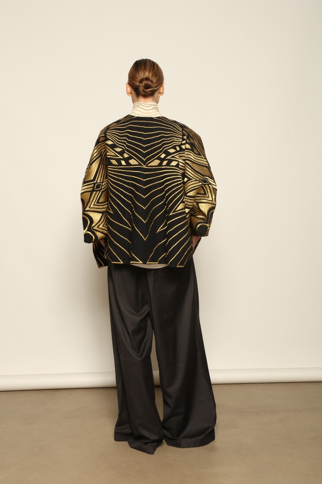 Model is wearing the Sunhera Reversible Jacket by Ka-Sha, a handcrafted cotton piece with rich gold stitching, offering two looks — black and gold or beige and gold — crafted over 65 hours and curated in the House of Woven Stories selection.