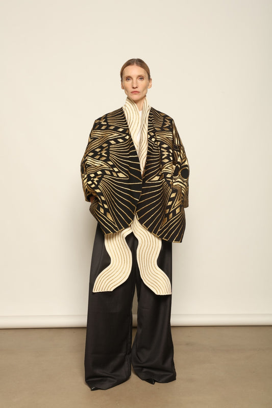 Model is wearing the Sunhera Reversible Jacket by Ka-Sha, a handcrafted cotton piece with rich gold stitching, offering two looks — black and gold or beige and gold — crafted over 65 hours and curated in the House of Woven Stories selection.