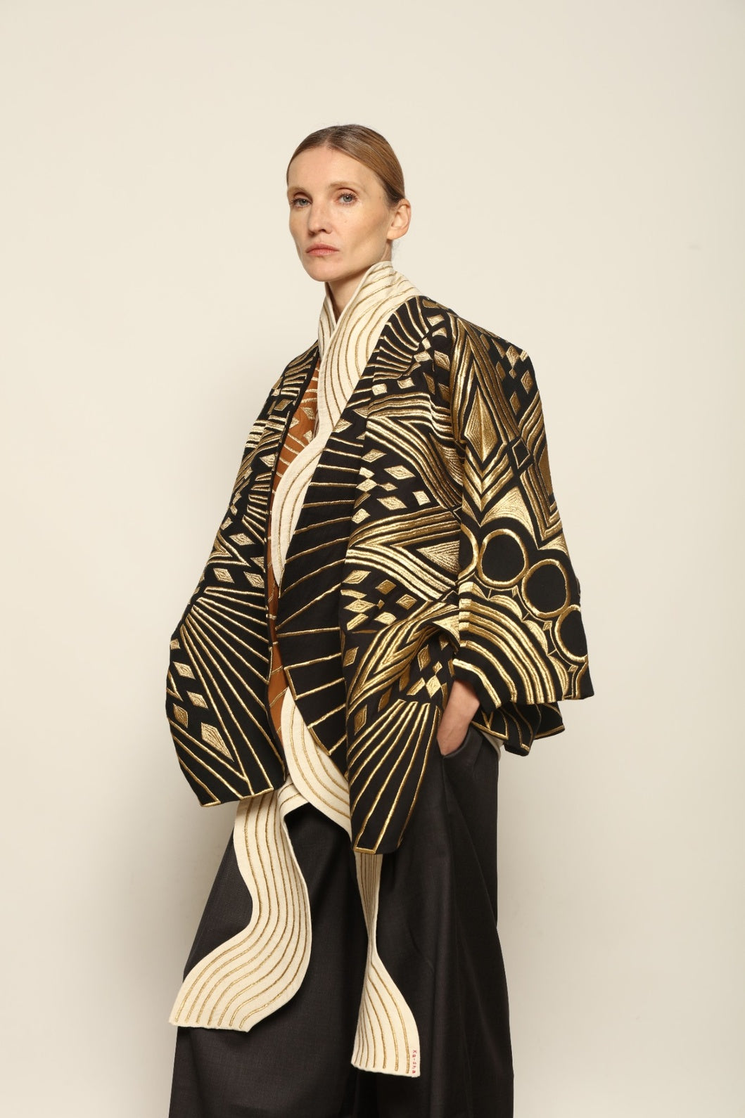 Model is wearing the Sunhera Reversible Jacket by Ka-Sha, a handcrafted cotton piece with rich gold stitching, offering two looks — black and gold or beige and gold — crafted over 65 hours and curated in the House of Woven Stories selection.