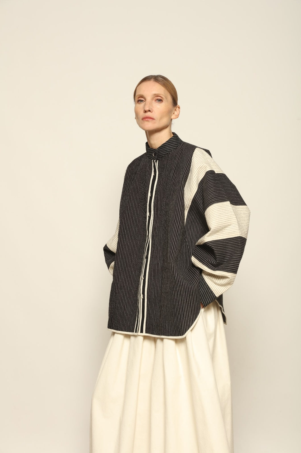 Model is wearing the Tri Bat Reversible Jacket by Ka-Sha, an artisanal reversible cotton jacket with bold black-and-white panels and wide sculptural sleeves, curated in the House of Woven Stories selection.