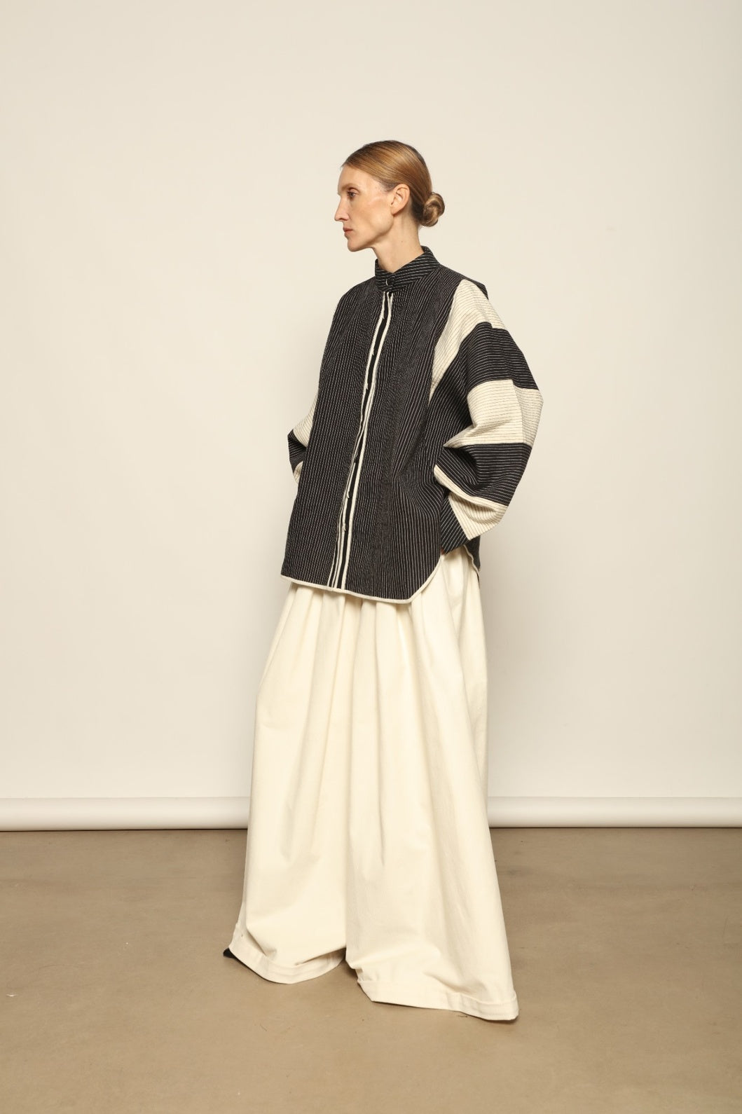 Model is wearing the Tri Bat Reversible Jacket by Ka-Sha, an artisanal reversible cotton jacket with bold black-and-white panels and wide sculptural sleeves, curated in the House of Woven Stories selection.