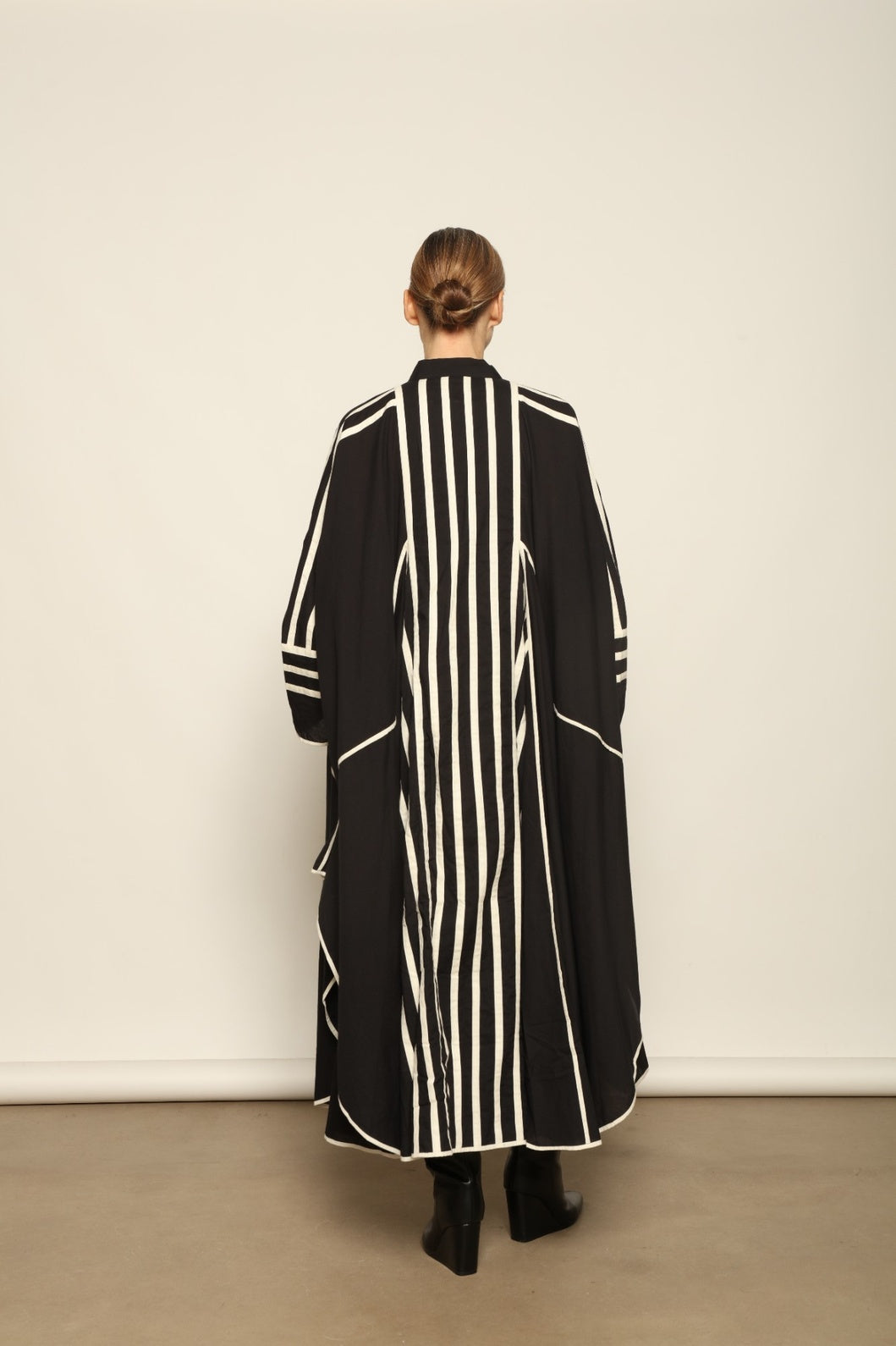 Model is wearing the Vibhor Tunic by Ka-Sha, a handcrafted black cotton tunic with off-white stripes, flowing sleeves and button-down front, curated in the House of Woven Stories selection.