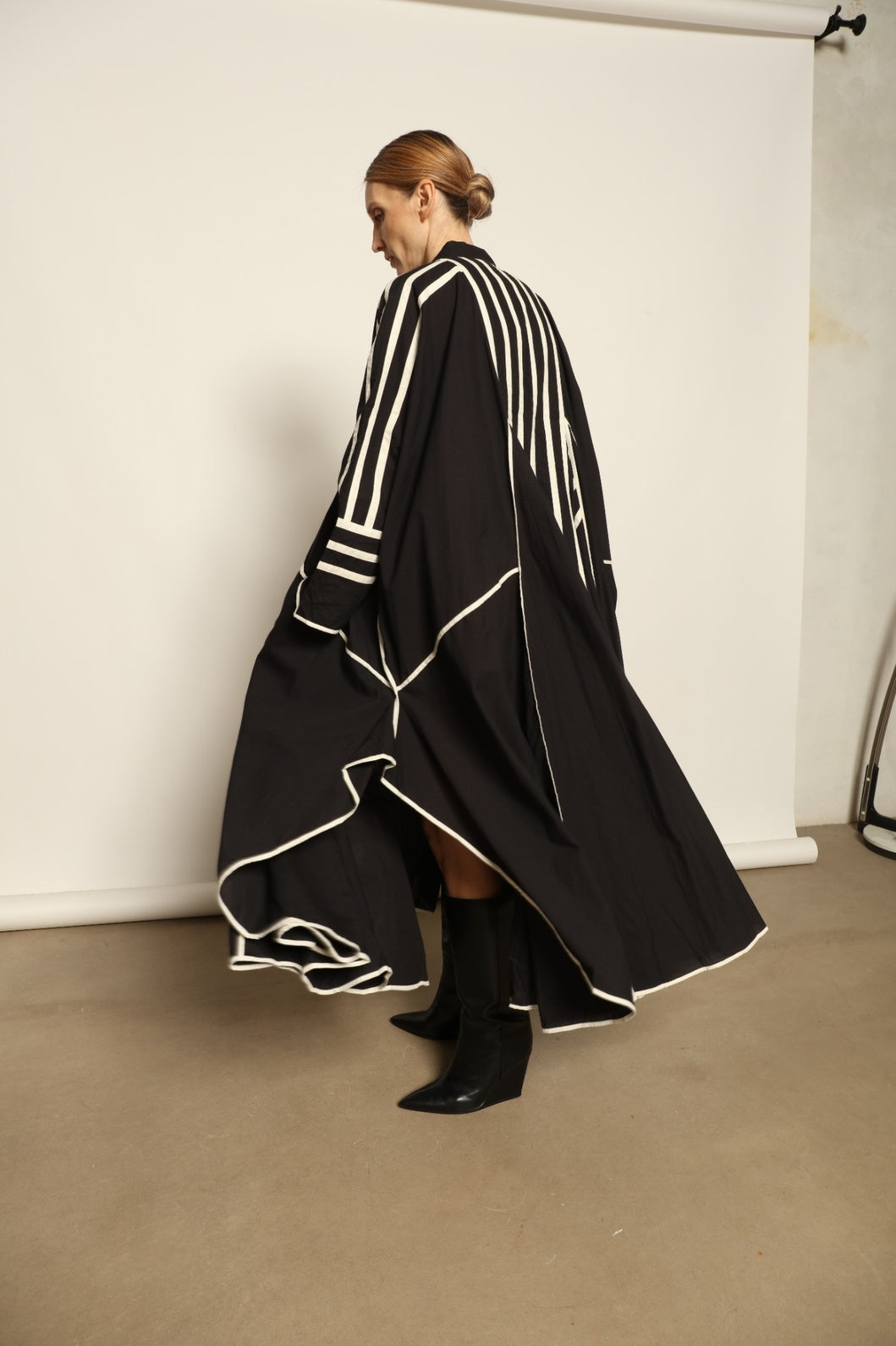 Model is wearing the Vibhor Tunic by Ka-Sha, a handcrafted black cotton tunic with off-white stripes, flowing sleeves and button-down front, curated in the House of Woven Stories selection.