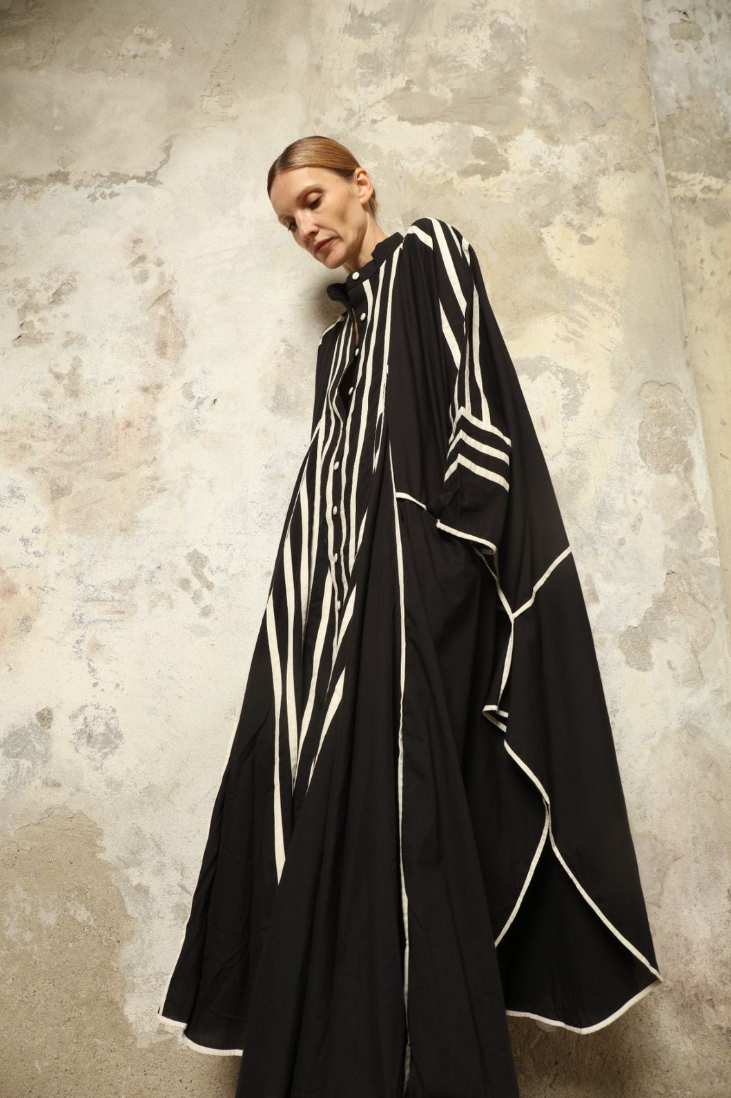 Model is wearing the Vibhor Tunic by Ka-Sha, a handcrafted black cotton tunic with off-white stripes, flowing sleeves and button-down front, curated in the House of Woven Stories selection.