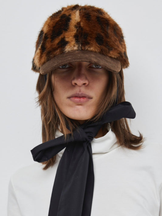 Model is wearing the Kate Leopard Cap by Maison Jejia, part of the House of Woven Stories selection, featuring black leopard print, detachable strap, structured design, and adjustable closure.