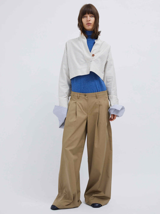 Model is wearing the Katherine Beige Pant by Maison Jejia, part of the House of Woven Stories selection, featuring long wide-leg fit, pleats for volume, belt loops, and side pockets.