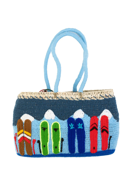 Undercover basket bag by Kilometre Paris inspired by winter exploration in Vail, Colorado, featuring embroidered mountain landscapes in blue and white on handwoven straw