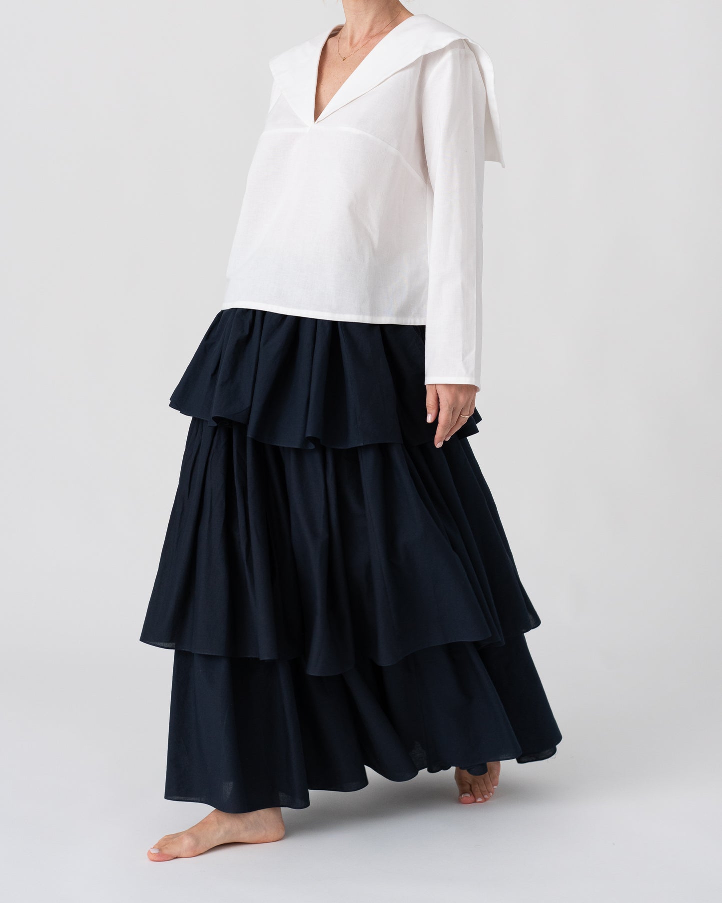 Model is wearing the Le Matelot White Blouse by Les Vacances d’Irina, a long-sleeved cotton blouse with sailor collar, handmade in Romania with artisanal detailing.
