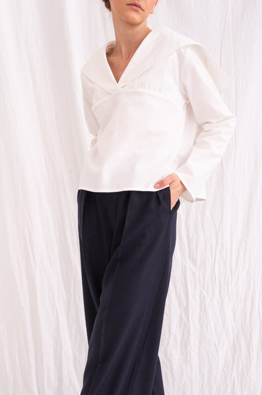 Model is wearing the Le Matelot White Blouse by Les Vacances d’Irina, a long-sleeved cotton blouse with sailor collar, handmade in Romania with artisanal detailing.