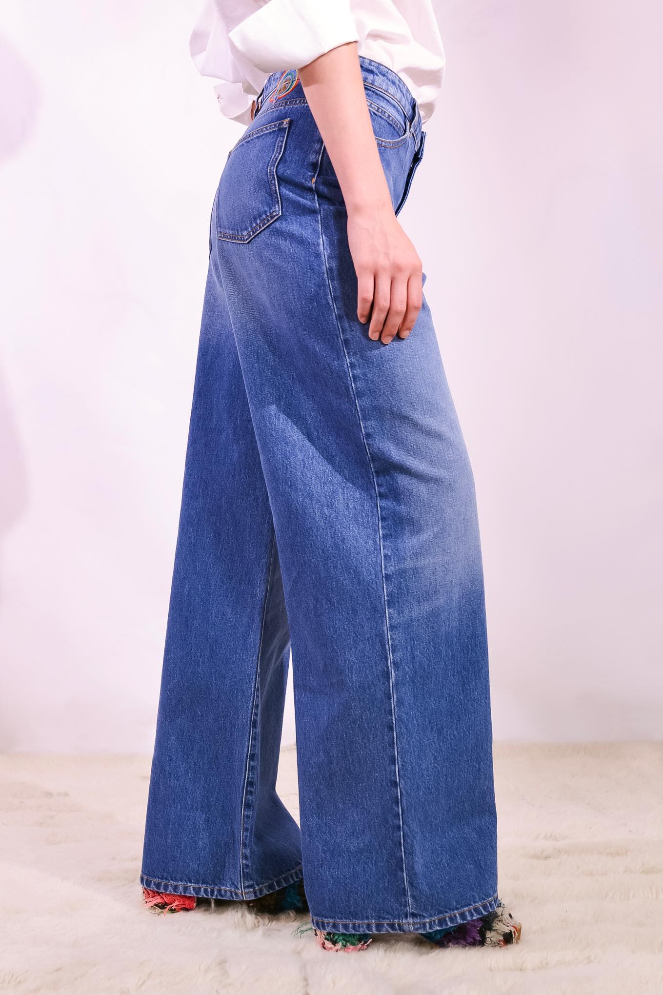 Model is wearing the Le Pantalon Baggy in Bleu d’Été Vintage by Happy Haus - relaxed boyfriend-style recycled denim jeans with wooden button, flower-shaped back pockets, and tobacco-colored topstitching.