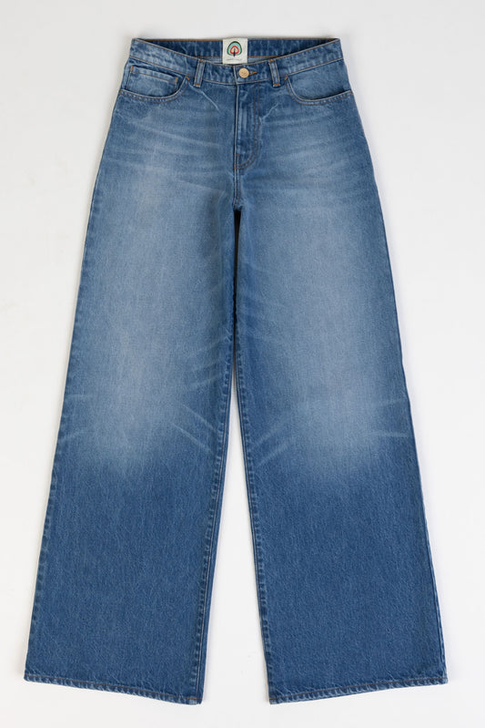 Model is wearing the Le Pantalon Baggy in Bleu d’Été Vintage by Happy Haus - relaxed boyfriend-style recycled denim jeans with wooden button, flower-shaped back pockets, and tobacco-colored topstitching.