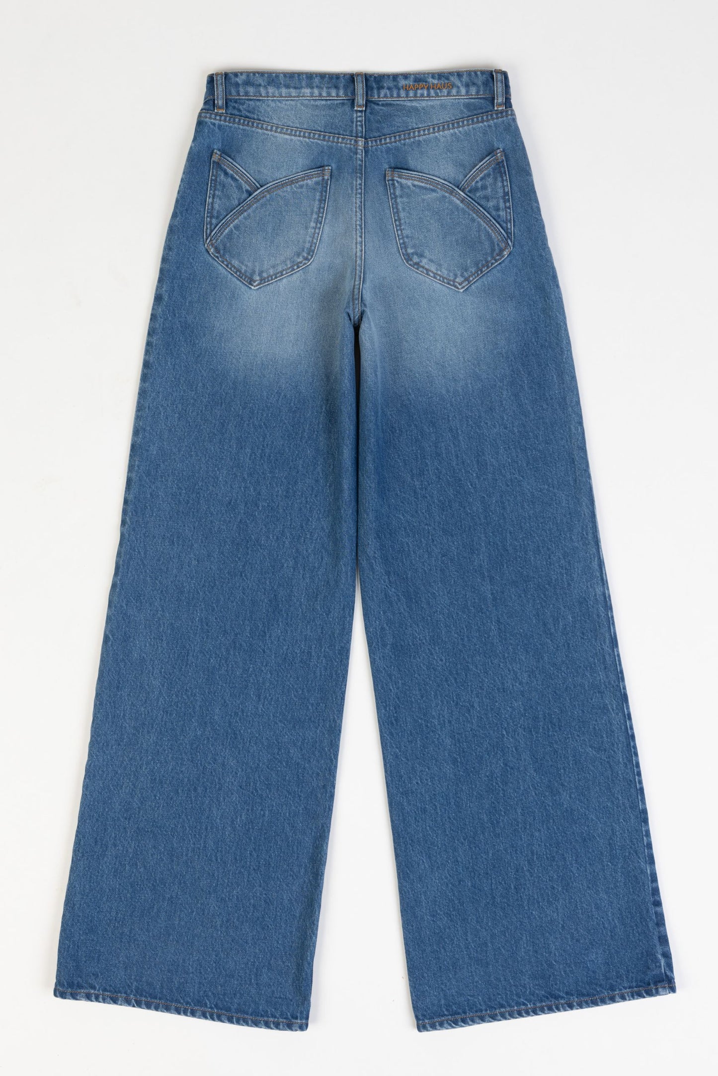 Model is wearing the Le Pantalon Baggy in Bleu d’Été Vintage by Happy Haus - relaxed boyfriend-style recycled denim jeans with wooden button, flower-shaped back pockets, and tobacco-colored topstitching.