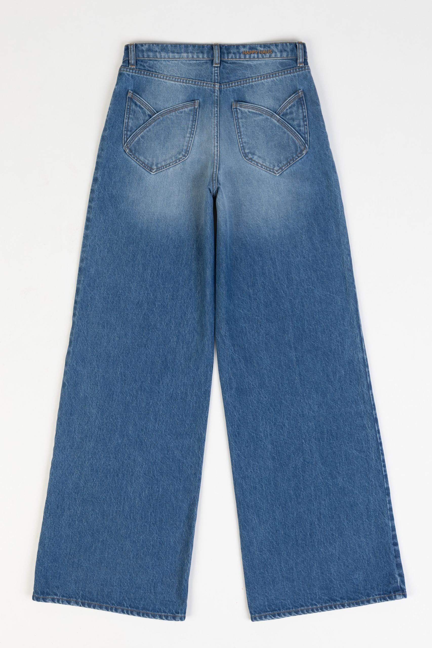 Model is wearing the Le Pantalon Baggy in Bleu d’Été Vintage by Happy Haus - relaxed boyfriend-style recycled denim jeans with wooden button, flower-shaped back pockets, and tobacco-colored topstitching.