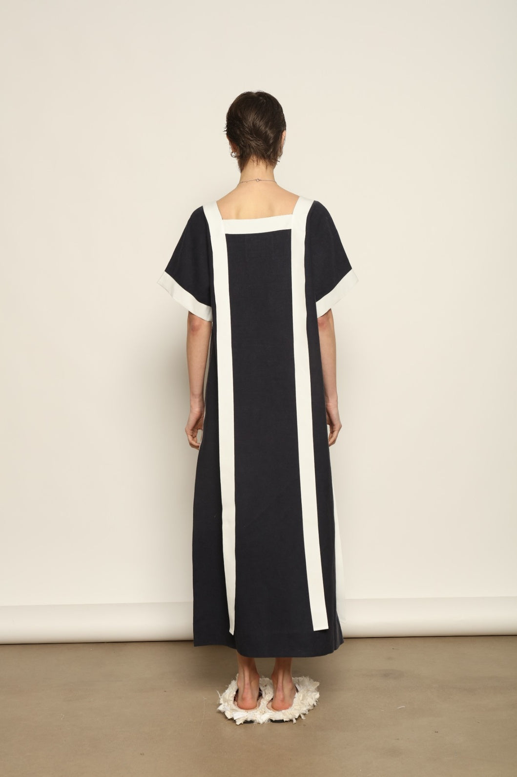 Model is wearing the Les Vacances d’Irina Astypalea kaftan linen dress in white with navy ribbon appliqués, handcrafted in Bucharest, from the House of Nomad Stories selection.