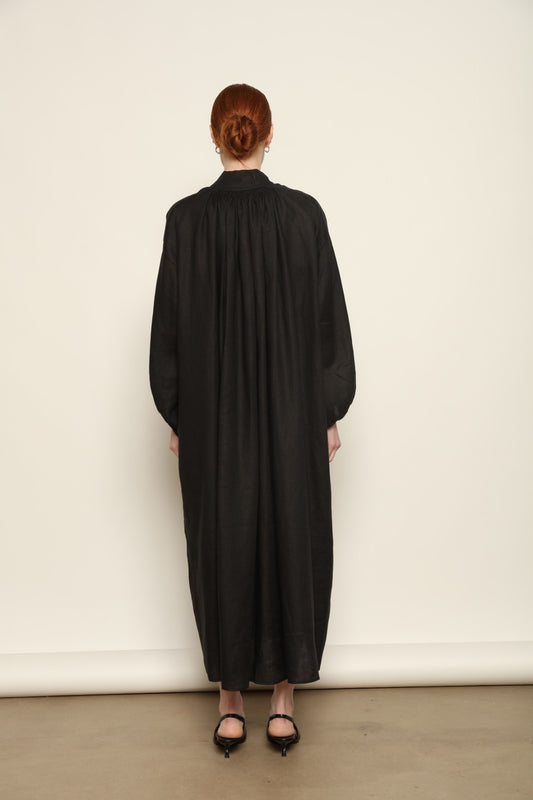 Model is wearing the Les Vacances d’Irina Black Sea Linen Dress, handcrafted from 100% linen with billowing sleeves and a gathered neckline, from the House of Nomad Stories selection.