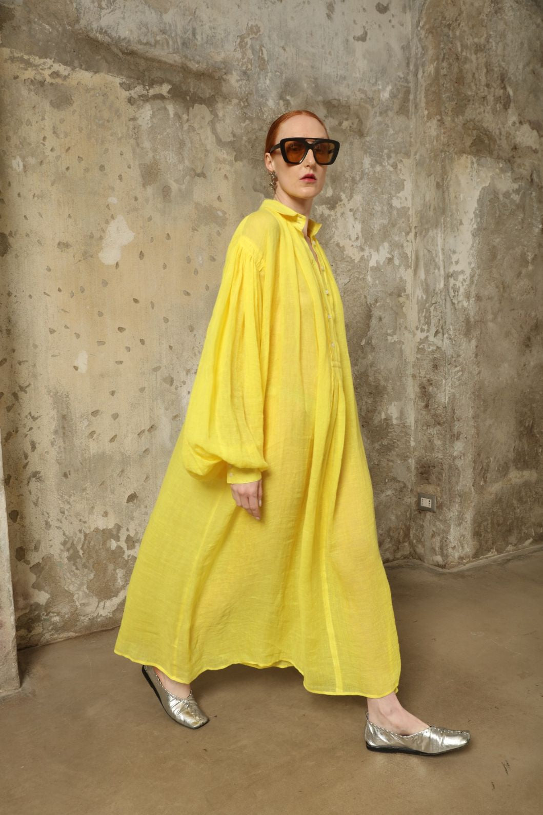 Model is wearing the Les Vacances d’Irina Carmen Linen Dress in Yellow, handcrafted from linen with dramatic wide sleeves, from the House of Nomad Stories selection.
