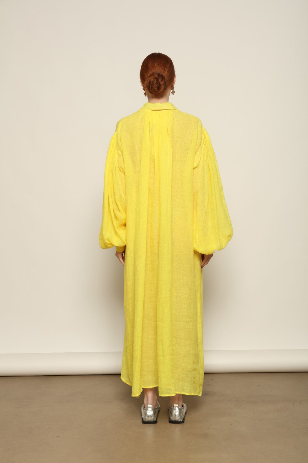 Model is wearing the Les Vacances d’Irina Carmen Linen Dress in Yellow, handcrafted from linen with dramatic wide sleeves, from the House of Nomad Stories selection.
