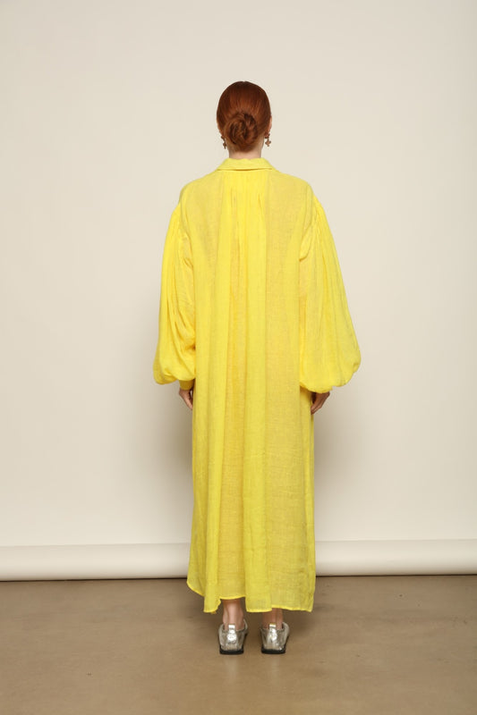 Model is wearing the Les Vacances d’Irina Carmen Linen Dress in Yellow, handcrafted from linen with dramatic wide sleeves, from the House of Nomad Stories selection.