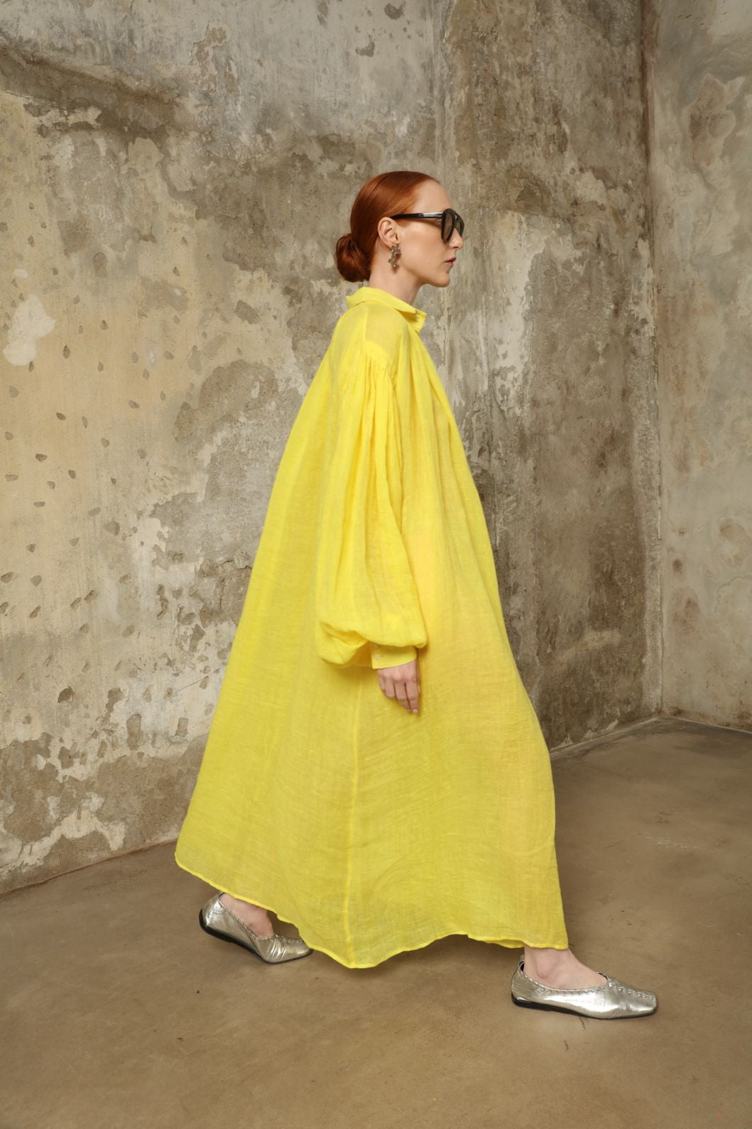 Model is wearing the Les Vacances d’Irina Carmen Linen Dress in Yellow, handcrafted from linen with dramatic wide sleeves, from the House of Nomad Stories selection.
